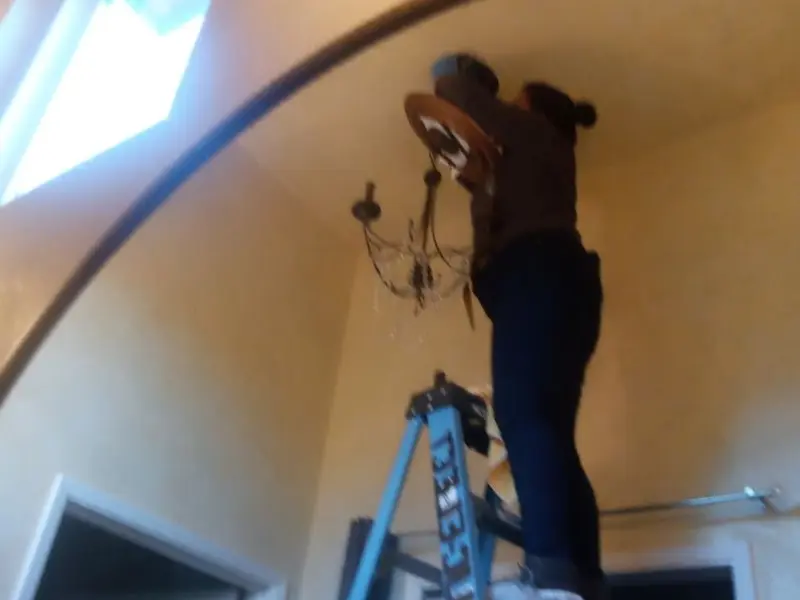Electrician installing a chandelier in a Commercial residence
